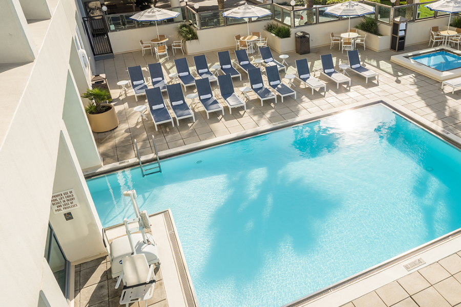 A clear blue hotel pool, with lounge chairs.