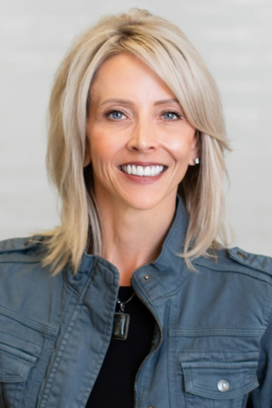 Professional headshot of Brook Kaufman against a dark background, smiling.